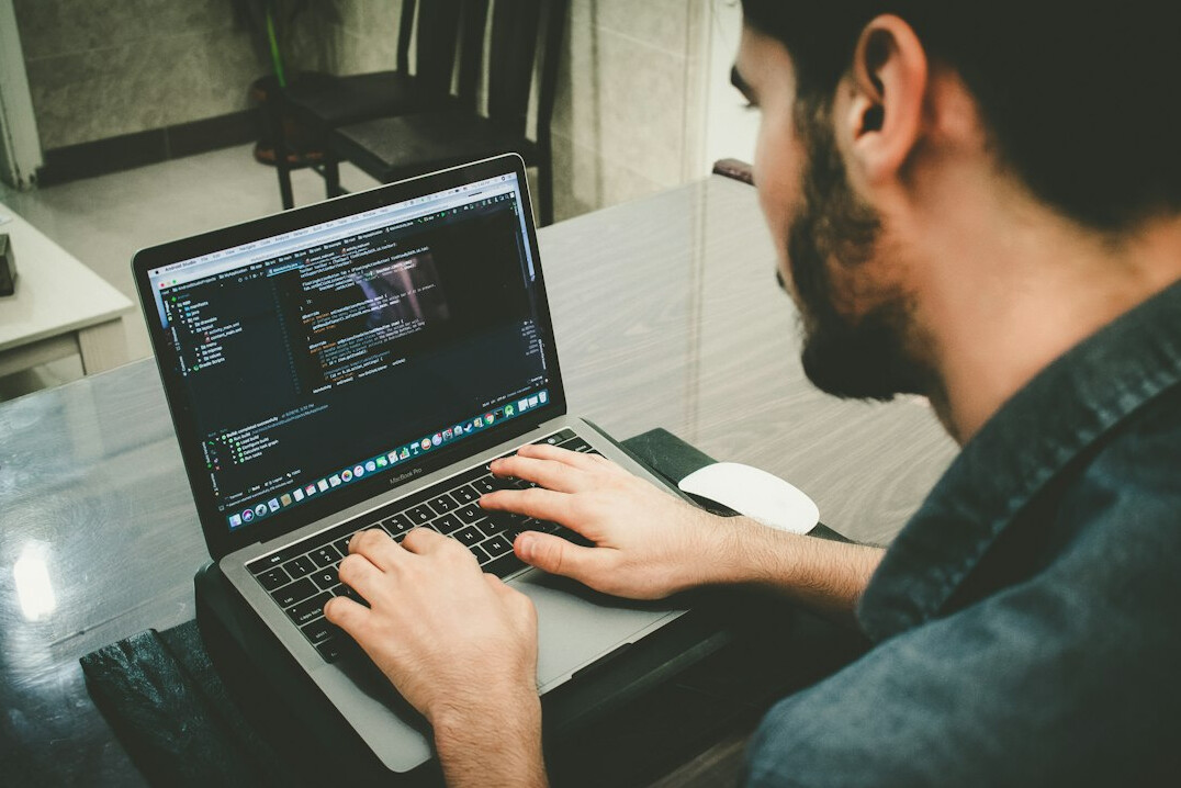 programmer writing code on laptop